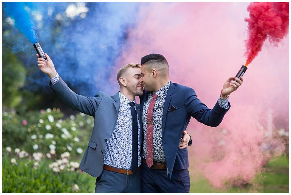 couple facing each other outside with colored smoke streamers