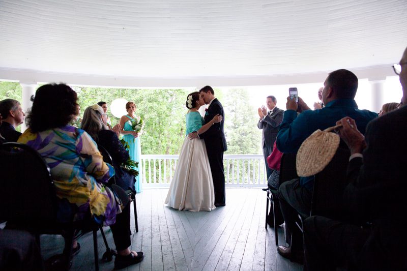 Veranda Wedding Ceremony cuban-flair-wedding-newlywed-couple-share-their-first-kiss-on-veranda-in-front-of-guests